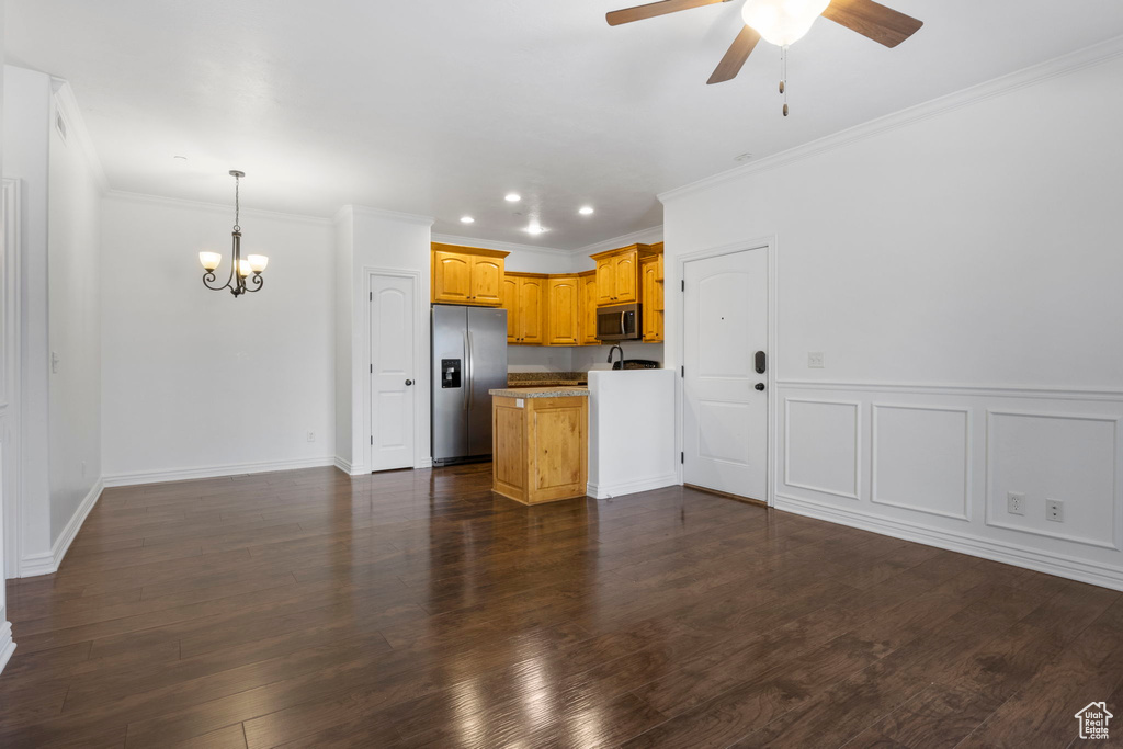 Kitchen featuring ceiling fan with notable chandelier, dark hardwood / wood-style floors, crown molding, and stainless steel appliances