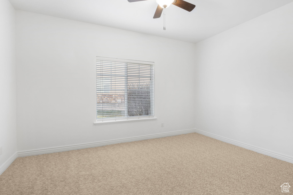 Carpeted spare room featuring ceiling fan