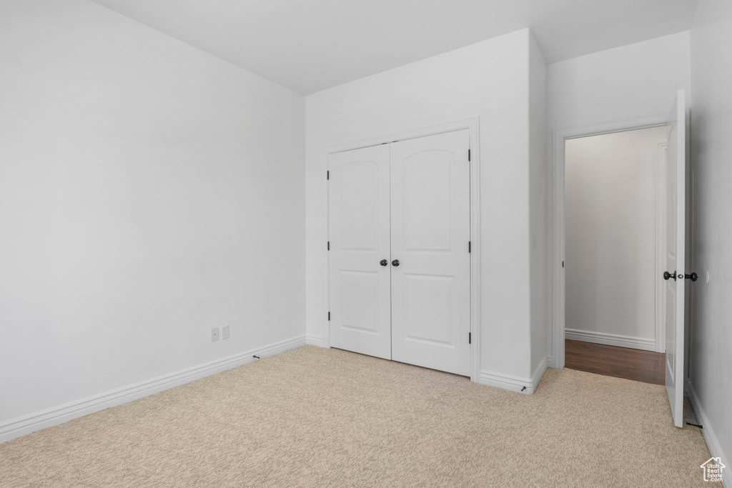 Unfurnished bedroom featuring light carpet and a closet