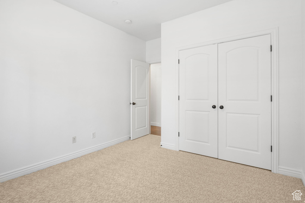 Unfurnished bedroom featuring light colored carpet and a closet