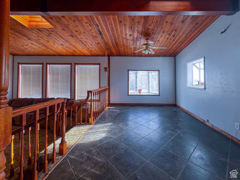 Unfurnished room featuring beamed ceiling, ceiling fan, and a skylight