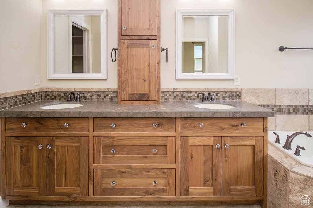 Bathroom with backsplash, tiled tub, and vanity