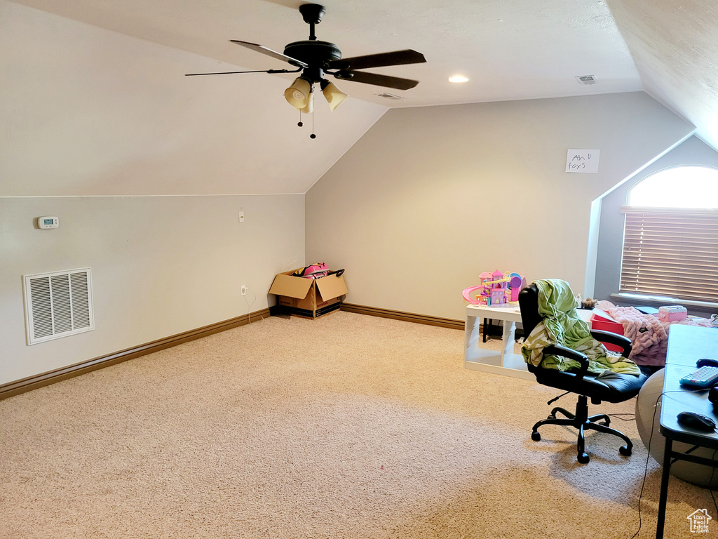 Interior space with ceiling fan, carpet floors, and vaulted ceiling