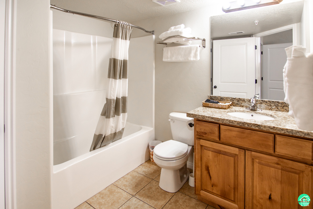 Bathroom featuring vanity, shower / bath combo, tile patterned flooring, and a textured ceiling