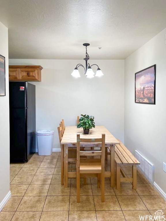 Dining space with a notable chandelier, light tile patterned floors, and a textured ceiling