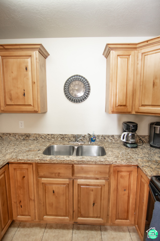 Kitchen with light tile patterned floors, light stone countertops, and stove