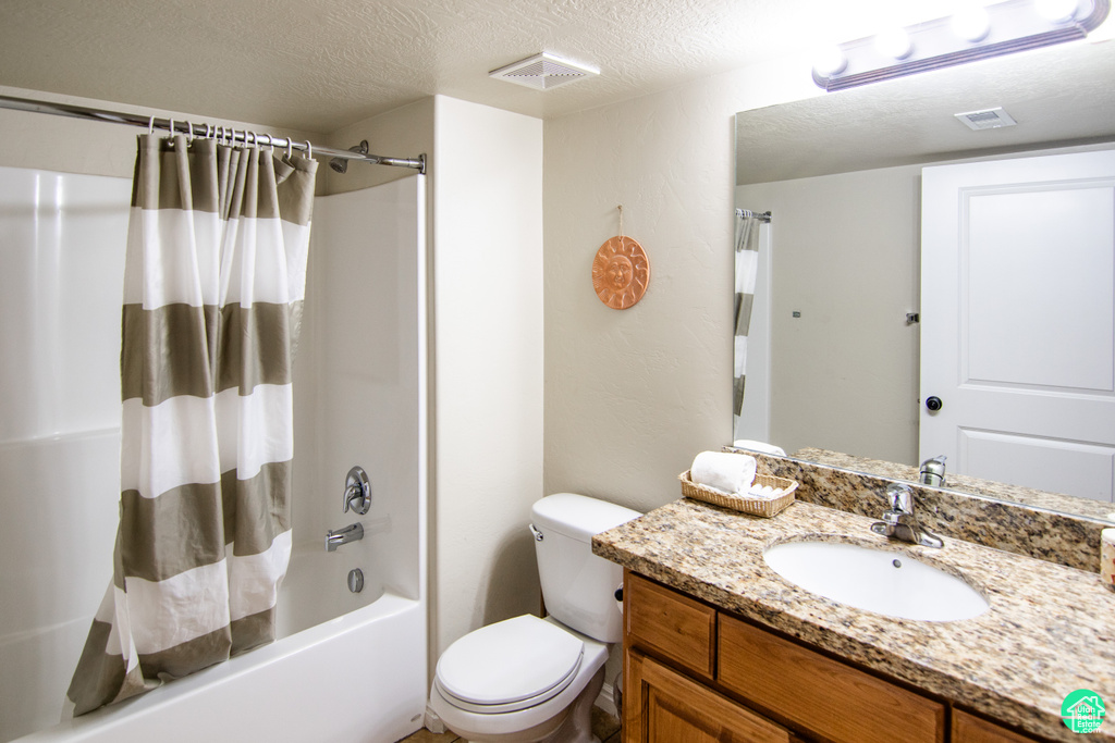Bathroom with shower / tub combo, vanity, and a textured ceiling