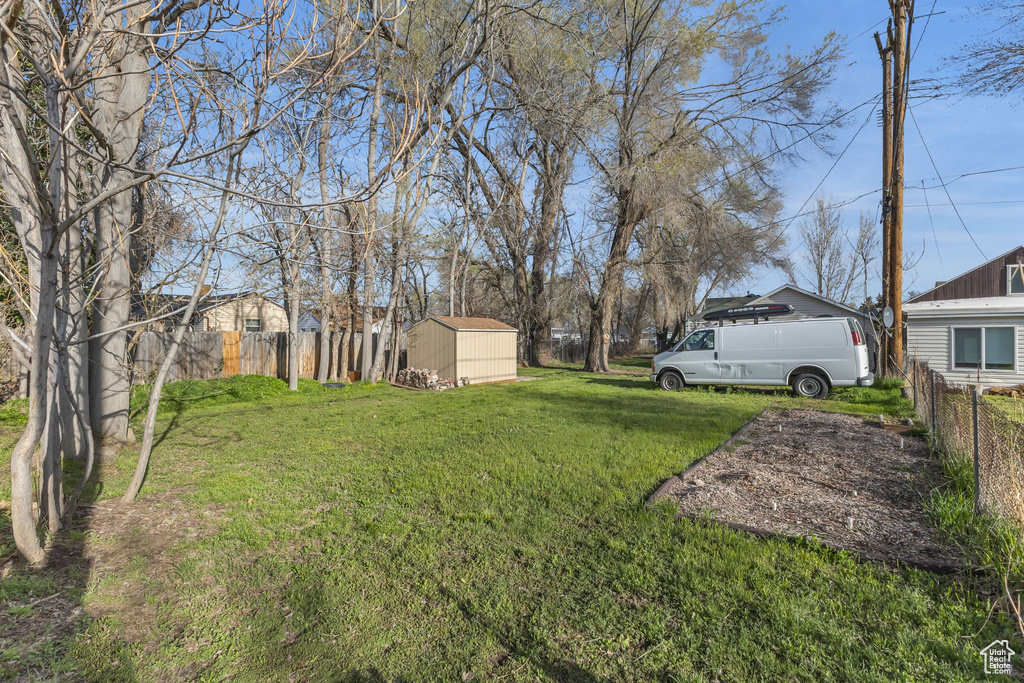 View of yard with a shed, fence, and an outdoor structure