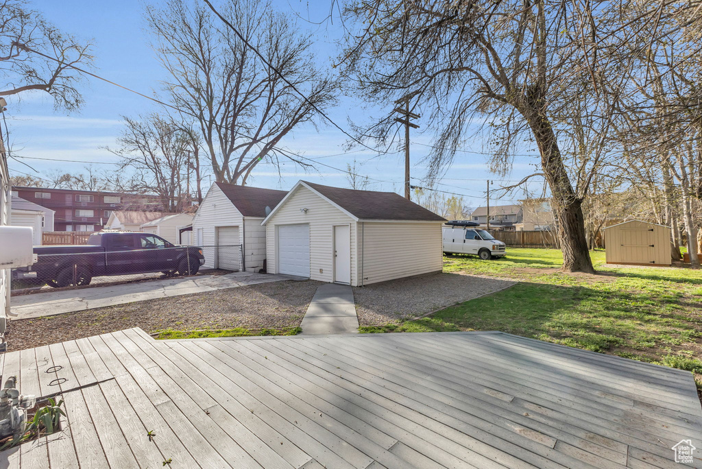 Deck featuring a yard, a detached garage, fence, and an outdoor structure