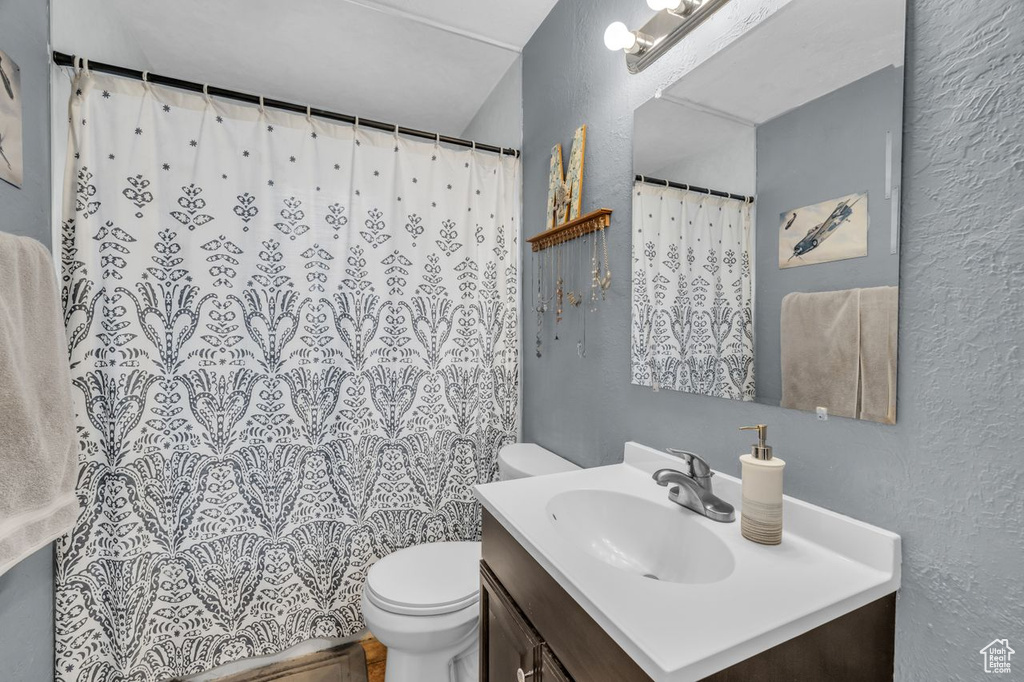 Bathroom with a shower with shower curtain, vanity, and toilet