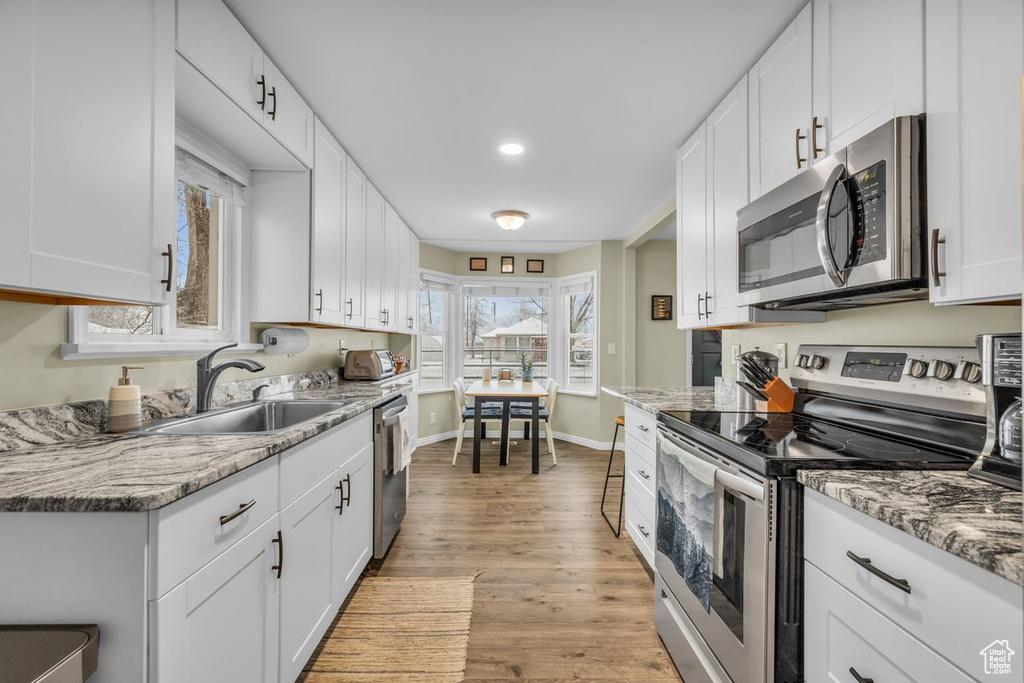 Kitchen with white cabinetry, sink, and appliances with stainless steel finishes