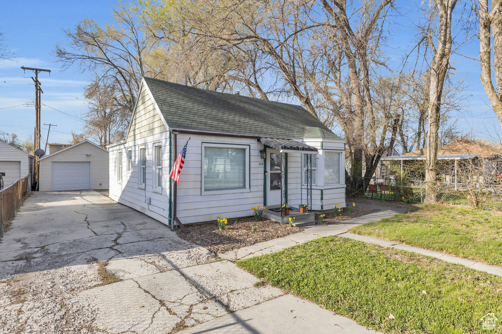 View of front of house with a shingled roof, a garage, aphalt driveway, an outdoor structure, and fence
