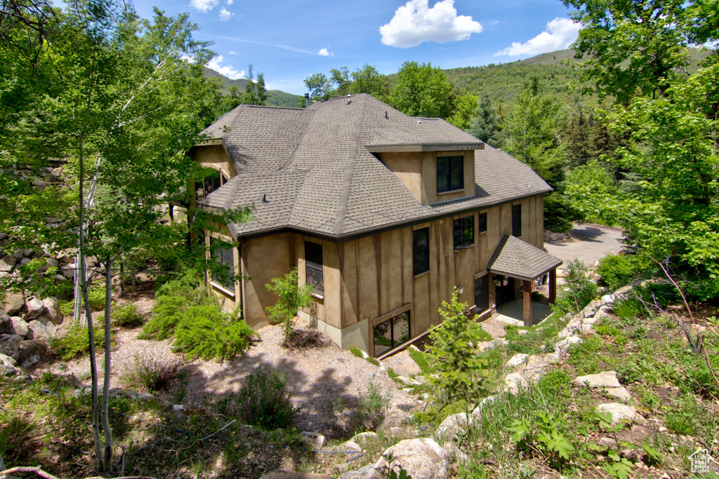 View of side of home featuring a shingled roof and board and batten siding