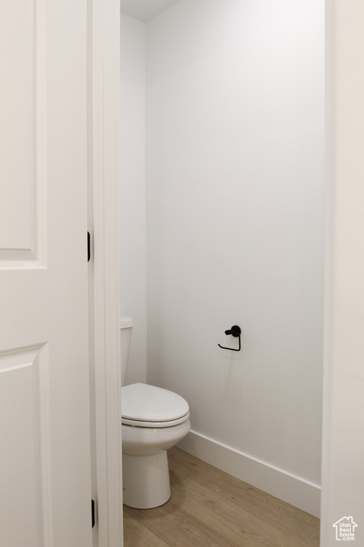 Bathroom with wood finished floors, toilet, and baseboards