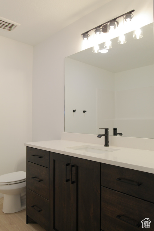 Bathroom with vanity, wood finished floors, and toilet