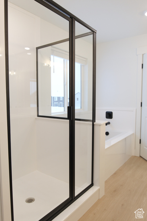 Full bathroom with wood finished floors, a stall shower, and a bath