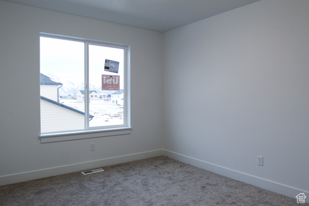 Carpeted spare room with healthy amount of natural light and baseboards