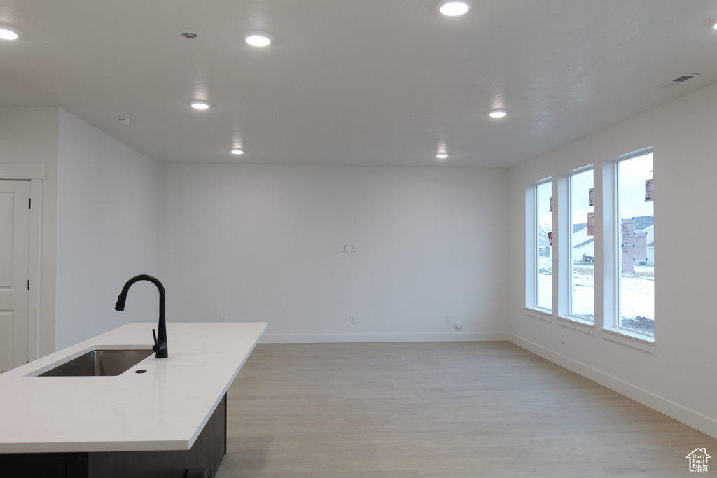 Kitchen with a sink, light wood-style flooring, recessed lighting, baseboards, and light countertops