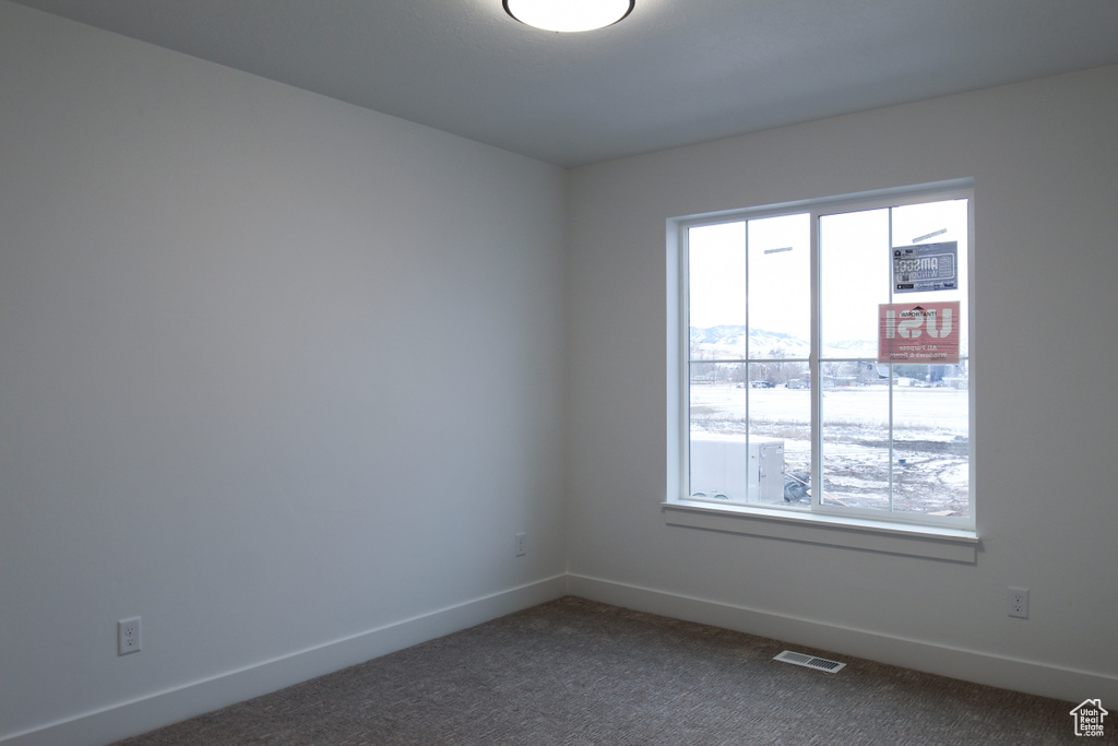 Spare room with plenty of natural light, dark carpet, baseboards, and a mountain view
