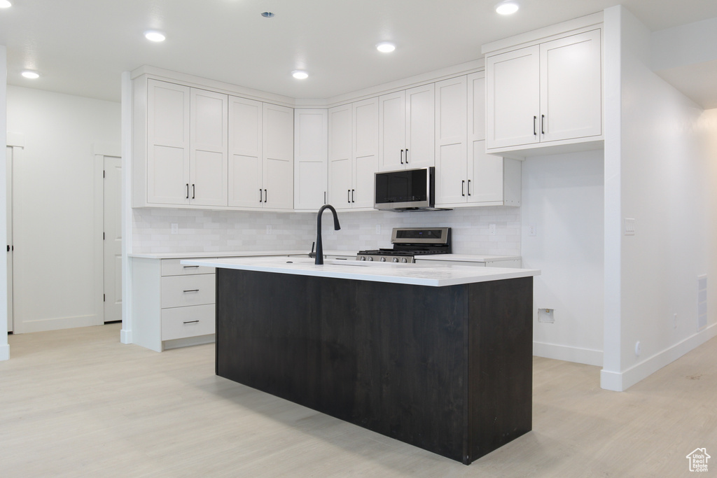 Kitchen featuring stainless steel appliances, baseboards, light wood-style floors, decorative backsplash, and recessed lighting