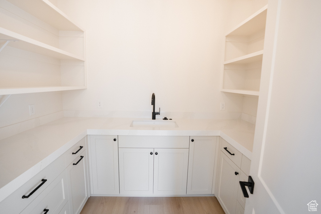 Laundry area with sink and light hardwood / wood-style flooring