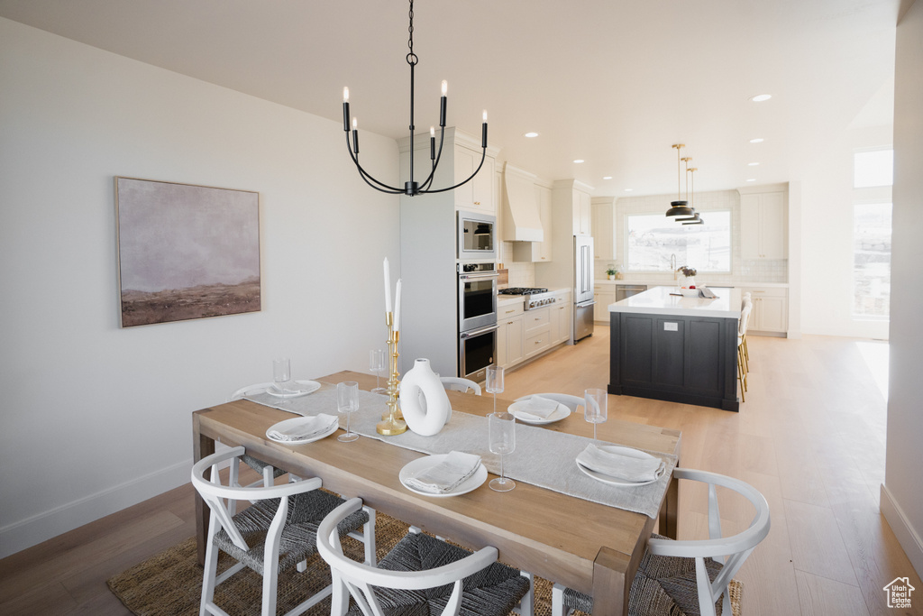 Dining room with light wood-type flooring and an inviting chandelier