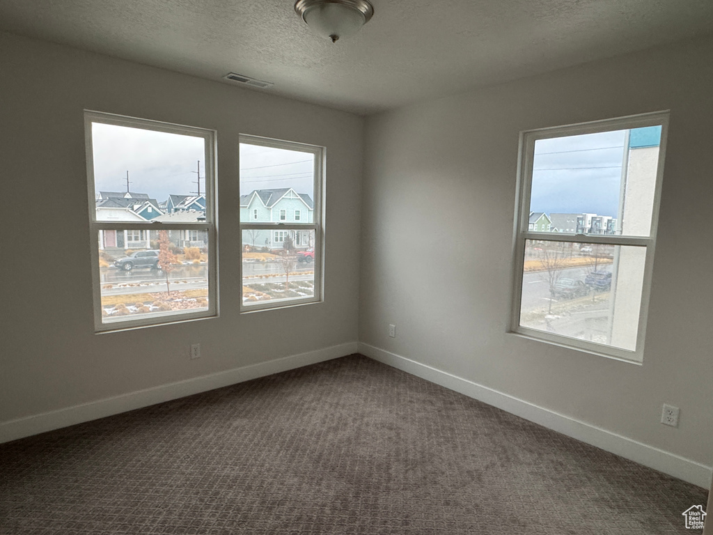 Empty room featuring a textured ceiling and carpet floors