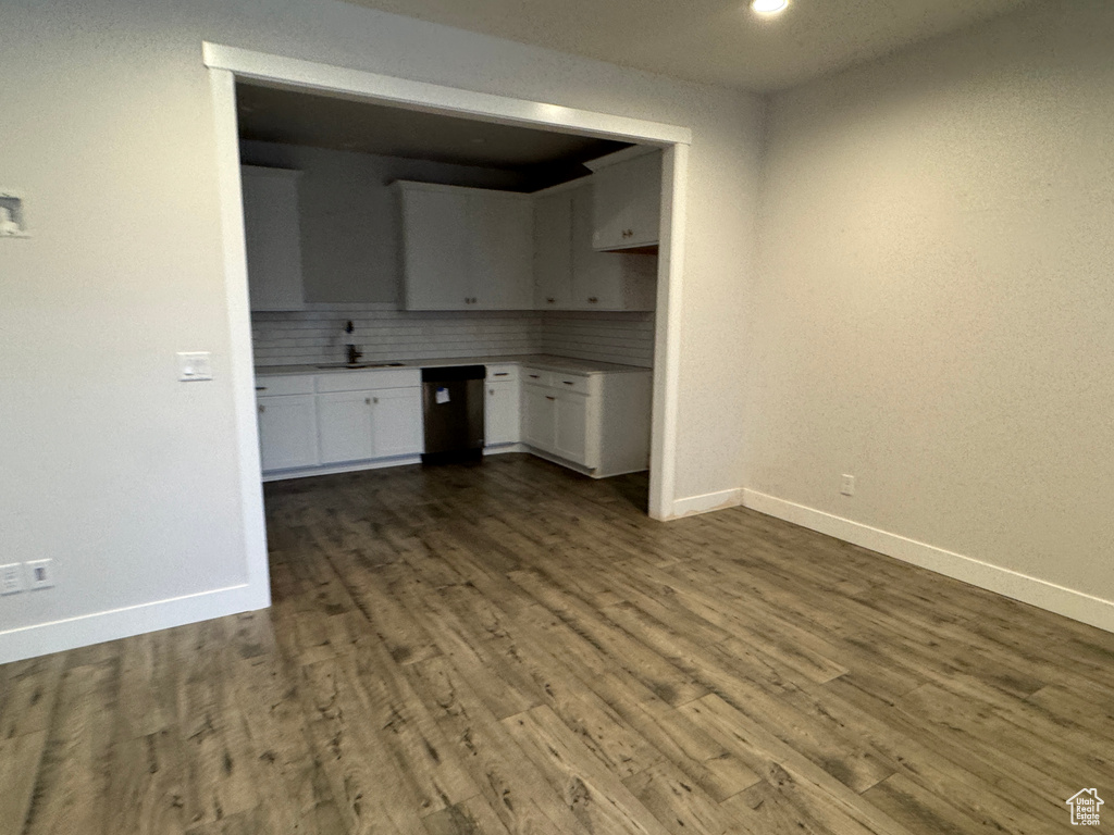 Kitchen with decorative backsplash, dark wood-type flooring, sink, dishwasher, and white cabinets