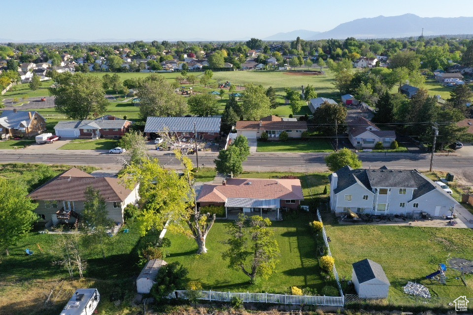 Aerial view of property and surrounding area featuring a mountainous background and nearby suburban area