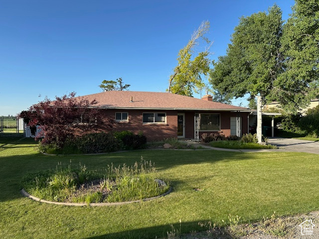 Ranch-style house with a front yard, concrete driveway, a chimney, and an attached carport