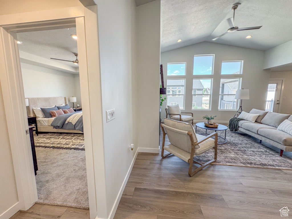 Living room with ceiling fan, vaulted ceiling, a textured ceiling, and wood finished floors