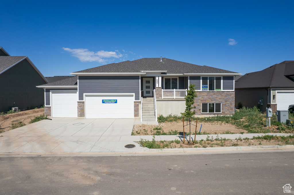 View of front of house featuring stone siding, an attached garage, driveway, and roof with shingles