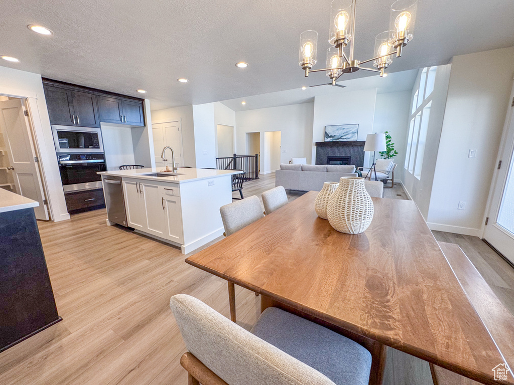 Dining space featuring light wood finished floors, recessed lighting, a chandelier, a fireplace, and a textured ceiling