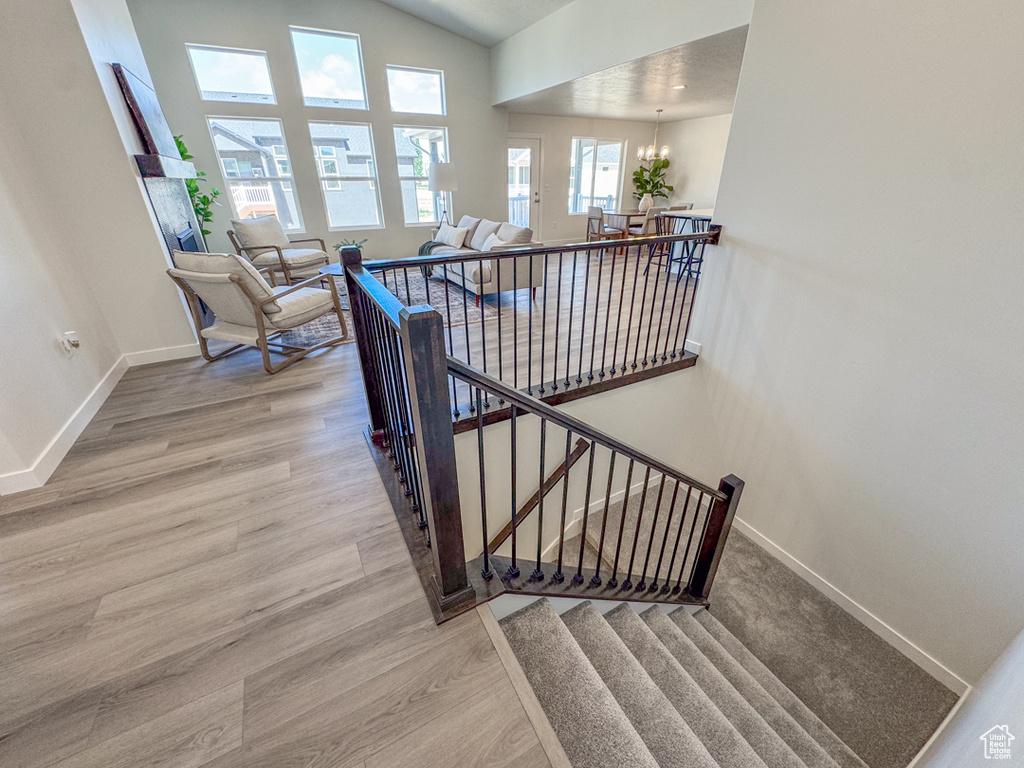 Staircase featuring wood finished floors, a chandelier, and vaulted ceiling