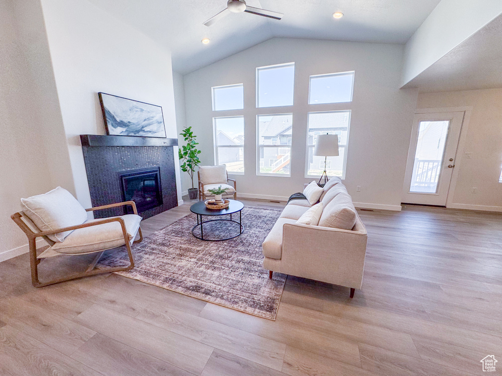 Living room featuring wood finished floors, a fireplace, a ceiling fan, and high vaulted ceiling