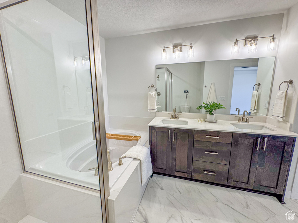 Full bath featuring a bath, marble finish flooring, double vanity, an enclosed shower, and a textured ceiling