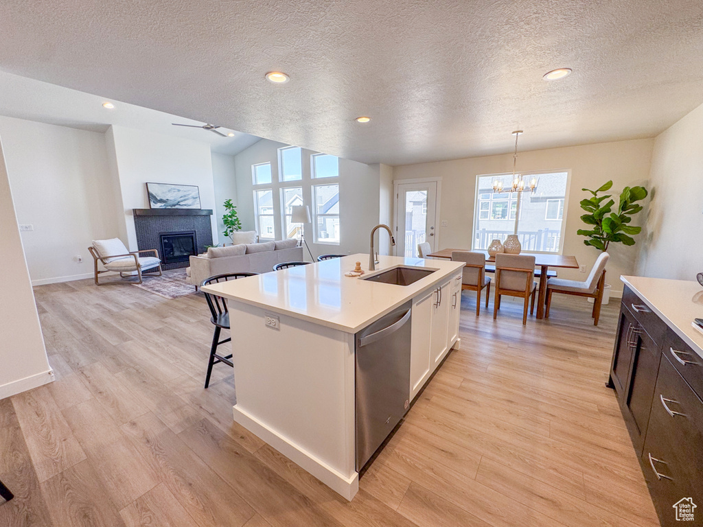 Kitchen featuring stainless steel dishwasher, light wood-type flooring, light countertops, a textured ceiling, and recessed lighting
