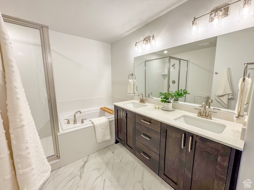 Bathroom featuring a stall shower, a bath, double vanity, marble look tile flooring, and a textured ceiling