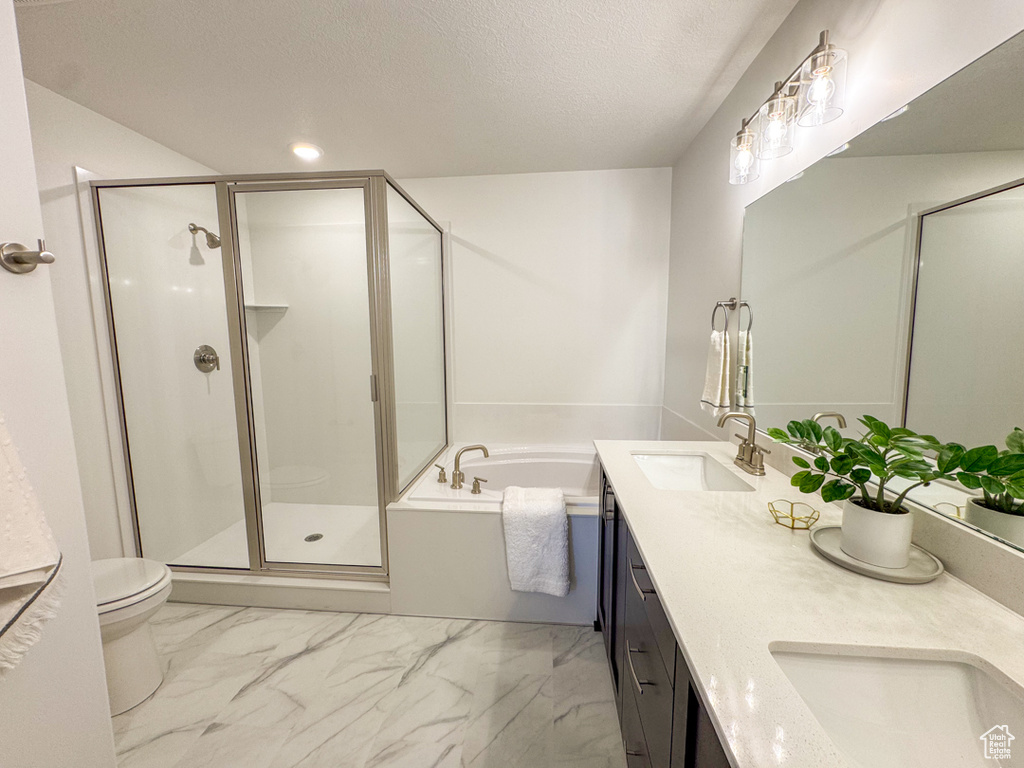 Full bathroom with marble look tile flooring, a shower stall, double vanity, a bath, and a textured ceiling