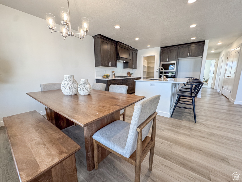 Dining room with light wood-style floors, a textured ceiling, recessed lighting, and a chandelier