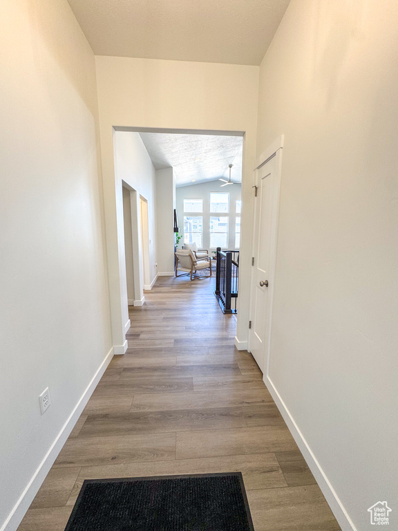 Corridor with wood finished floors and an upstairs landing