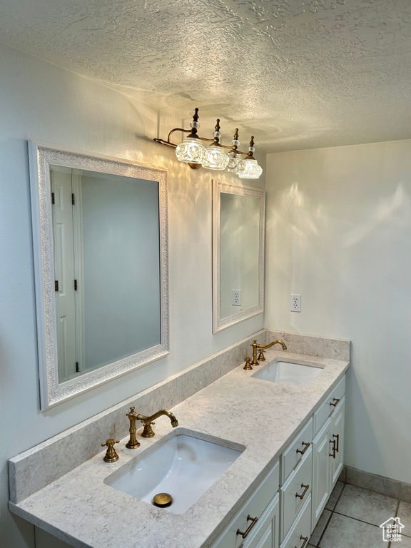 Bathroom with tile patterned flooring, vanity, and a textured ceiling