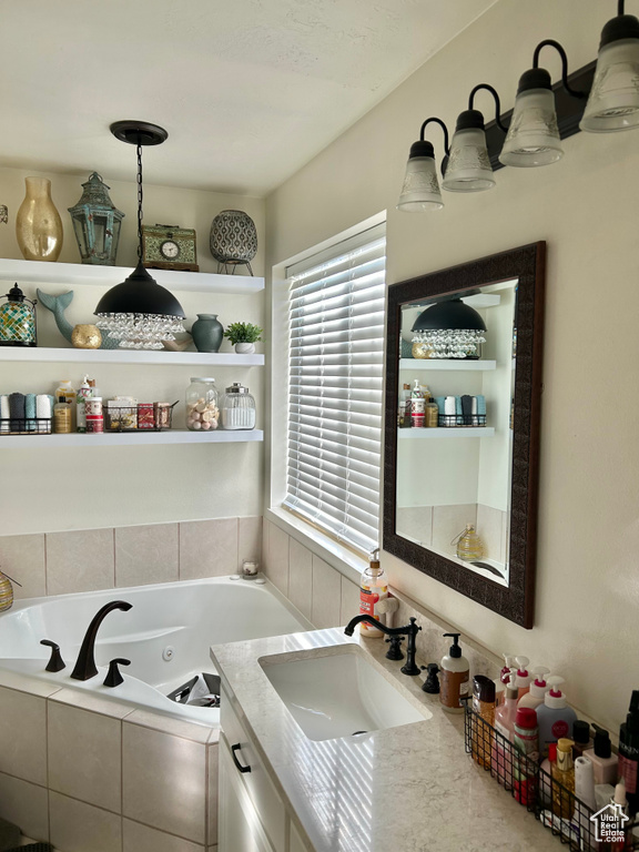 Bathroom featuring vanity and tiled bath