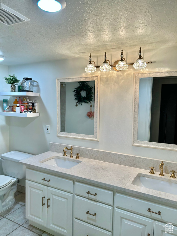 Bathroom featuring tile patterned floors, vanity, a textured ceiling, and toilet