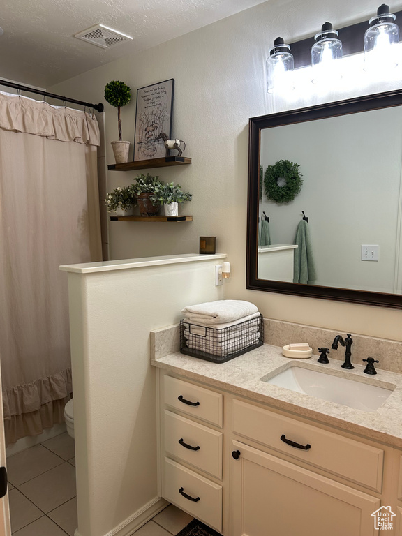 Bathroom featuring tile patterned flooring, vanity, toilet, and walk in shower