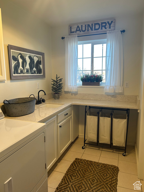 Kitchen with light tile patterned flooring, washer / clothes dryer, white cabinetry, and sink