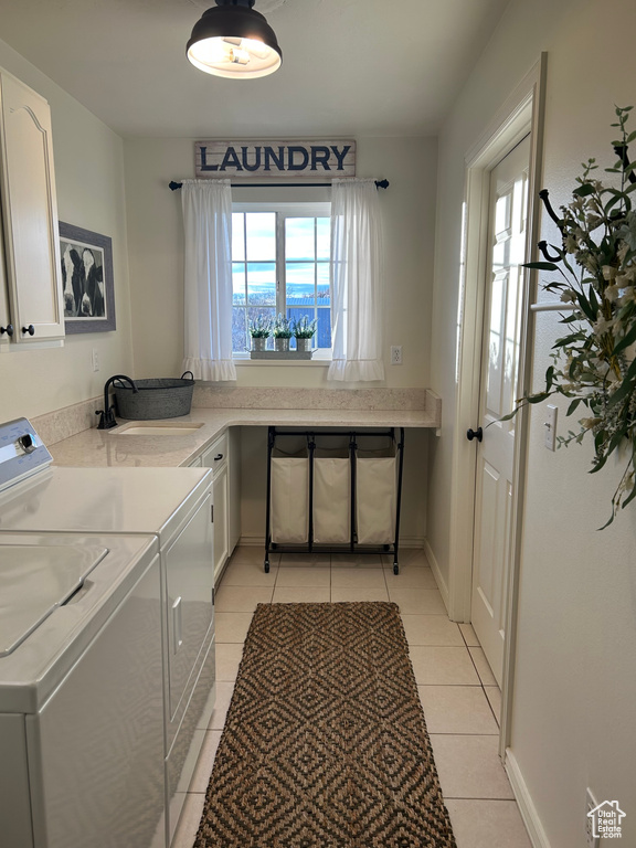 Clothes washing area featuring cabinets, separate washer and dryer, light tile patterned flooring, and sink