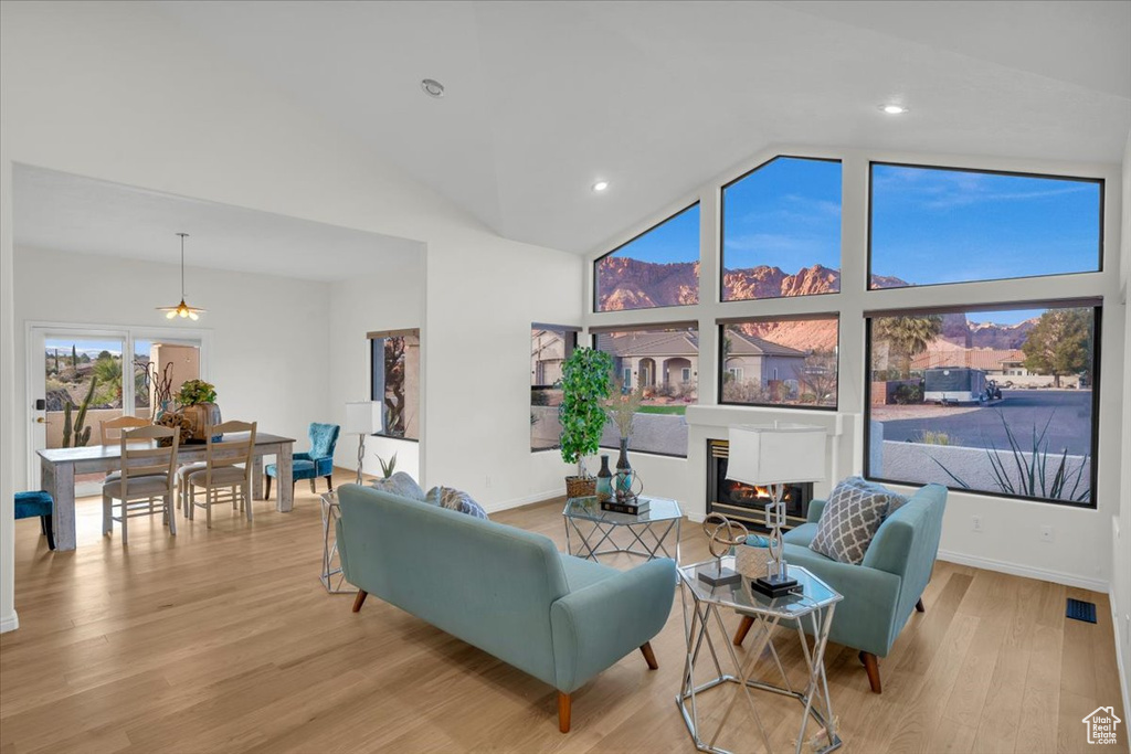 Living room with ceiling fan, light hardwood / wood-style floors, and high vaulted ceiling