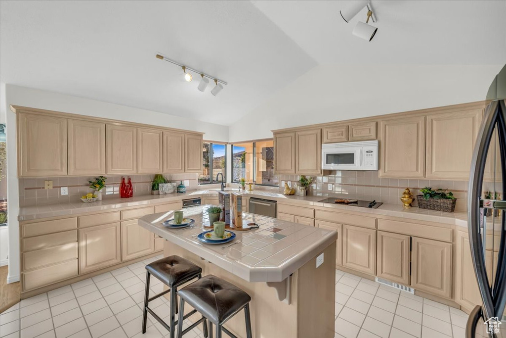 Kitchen with dishwasher, a center island, tasteful backsplash, tile countertops, and refrigerator