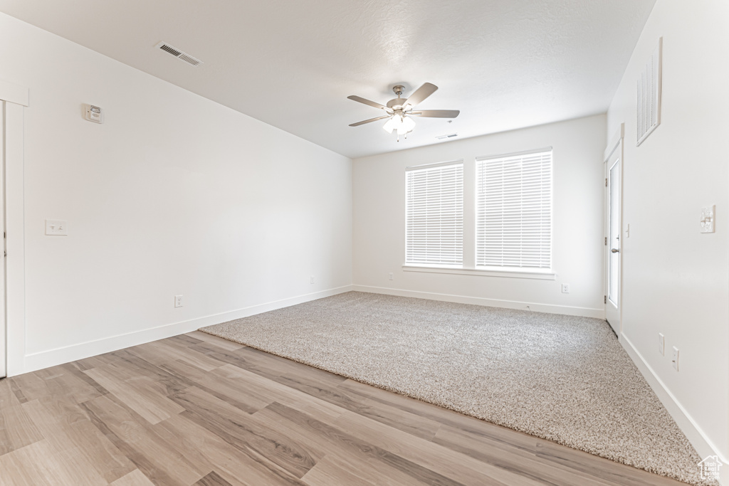Empty room featuring light wood-style floors, ceiling fan, and baseboards